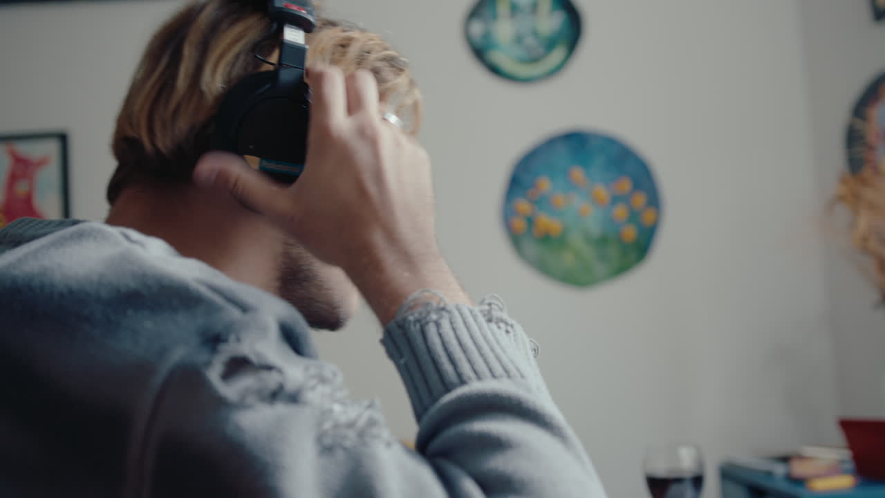 Musician with Guitar Putting on Headphones at Home Recording Studio