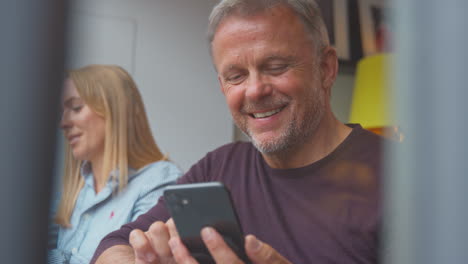 Customers-In-Coffee-Shop-Window-Working-On-Laptops-And-Browsing-On-Mobile-Phone