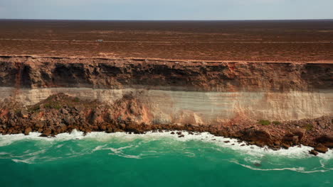 Toma-Aérea-Del-Carro-Derecho-De-La-Gigantesca-Pared-Del-Acantilado-Y-La-Costa-Del-Océano-Debajo-En-Verano