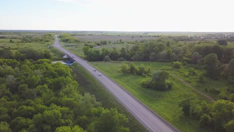 aerial view of a country road with a bridge and surrounding landscape
