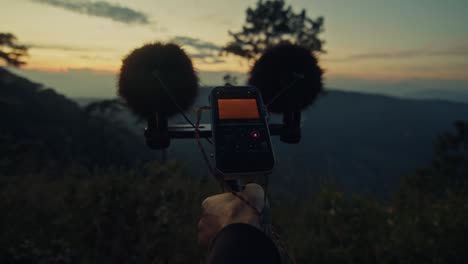 handheld audio recorder at sunrise mountaintop
