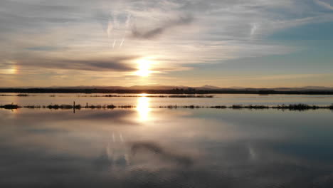 aerial view flying from right to left. beautiful sunset over the rice field covered with water. perfectly smooth surface of water in albufera national park, valencia spain