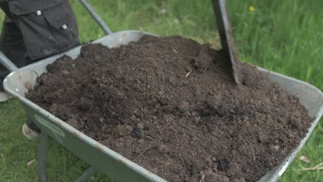 mixing soil in wheelbarrow with shovel removing roots