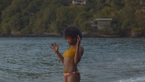 Mujer-Sexy-En-Bikini-Juega-Con-Ella-En-La-Playa-Con-Casa-De-Playa-Y-Una-Montaña-En-El-Fondo