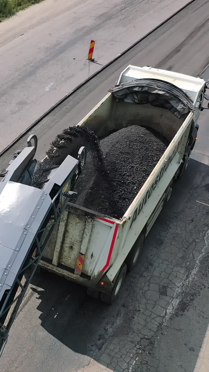 Machinery work construction road. Industrial dumper trucks working on highway construction site. Vertical video