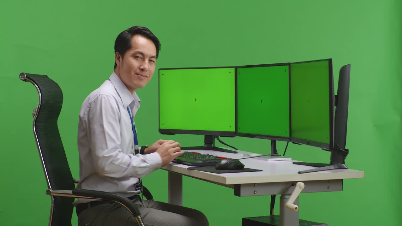 여러 개의 녹색 화면 모니터와 함께 책상에 앉아있는 사람