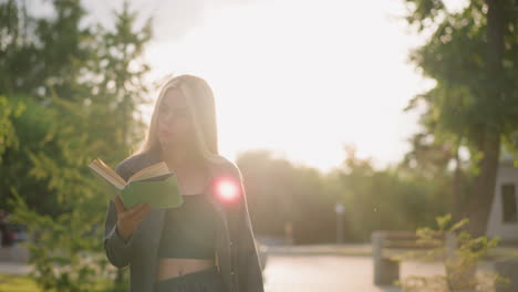 young lady walking while reading a book closes it thoughtfully, looking away as the sunlight illuminates her surroundings, the background features greenery with soft, warm light and subtle blur