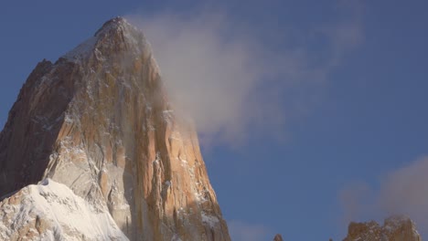 Up-close-static-view-of-Mount-Fitz-Roy-at-sunrise,-zooming-in-on-the-rocky-peak-and-clouds-against-the-blue-sky,-Patagonia,-Argentina