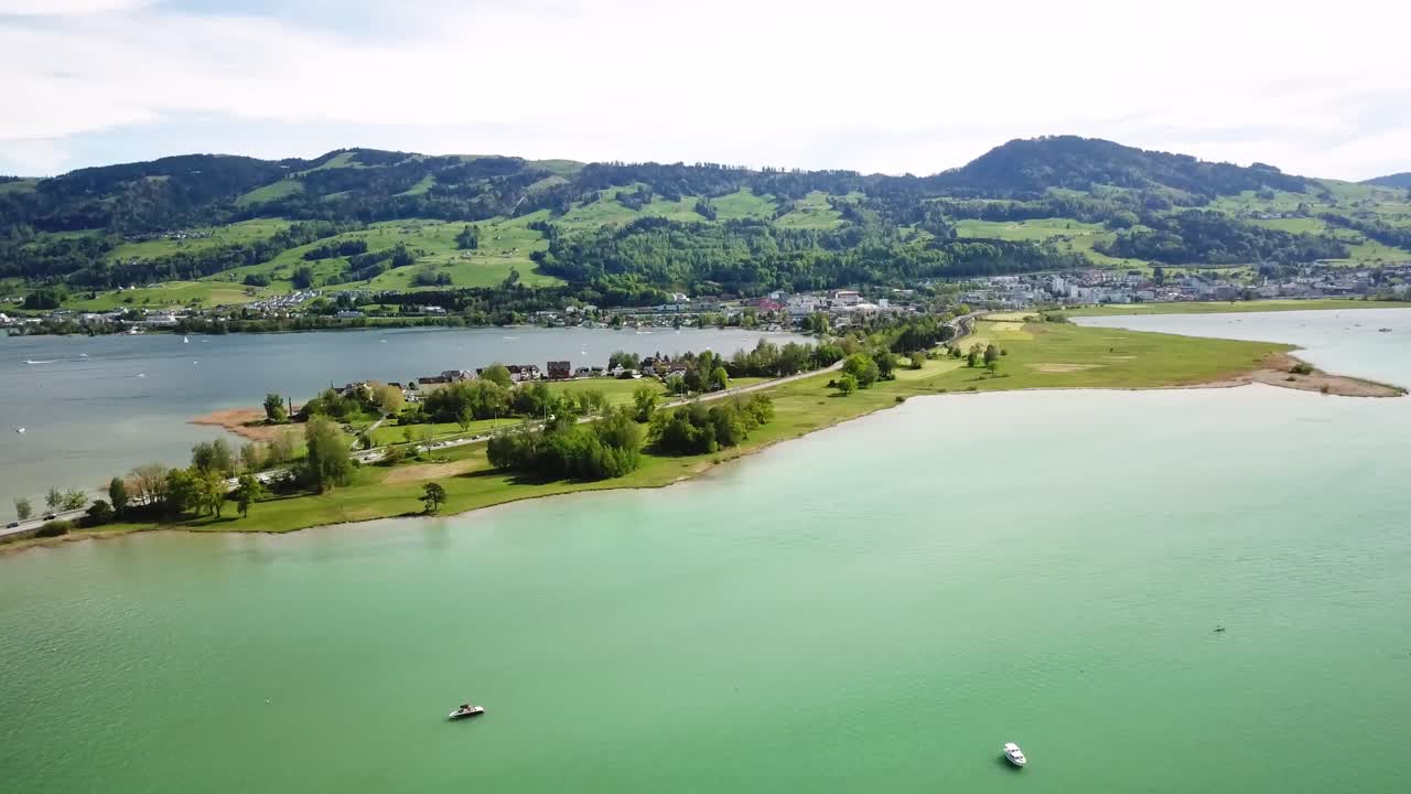 Rose city Rapperswill town is connected to Hurden by a peninsula, creating a scenic landscape with lush greenery and beautiful Zurichsee lake views. Freienbach, Schwyz, Switzerland, drone panning