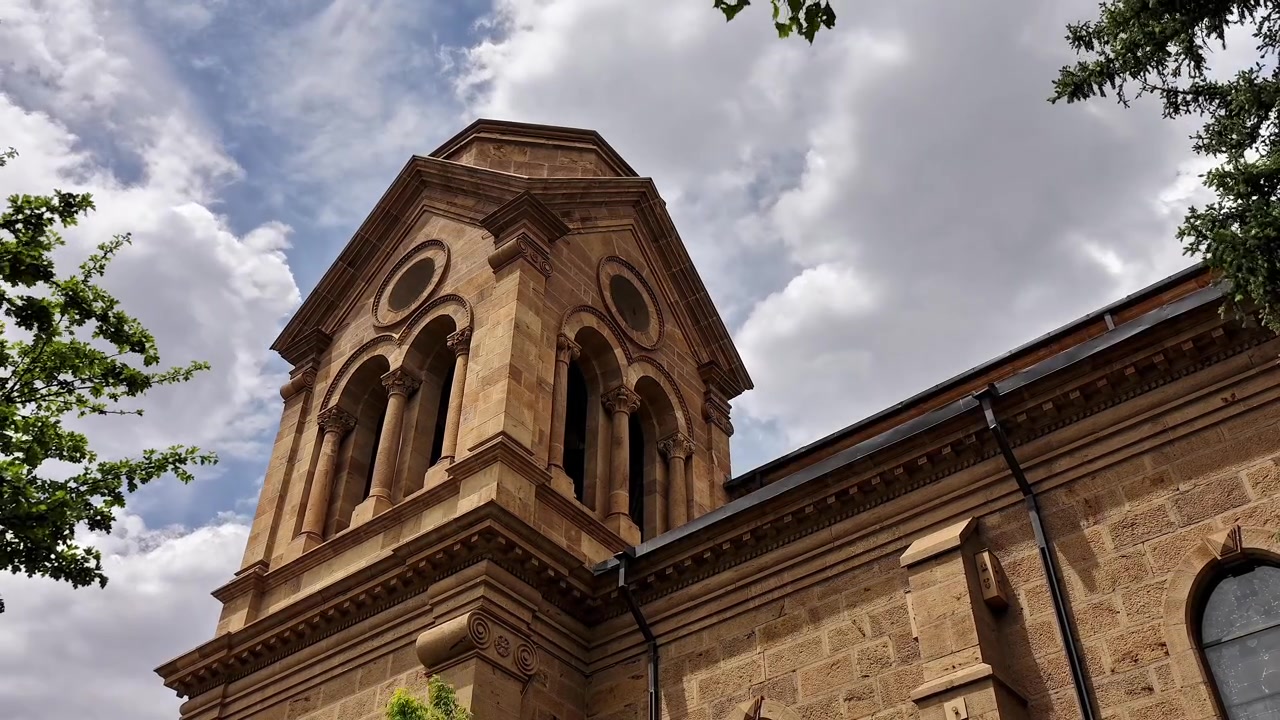 Un timelapse statico in 4K cattura nuvole drammatiche che si muovono dietro una tradizionale torre di cattedrale del sud-ovest. Filmati architettonici cinematografici rivelano luce mutevole e un contrasto suggestivo contro la guglia di pietra.