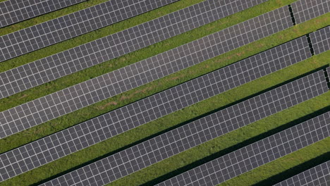 Girar-En-Una-Enorme-Planta-De-Energía-Solar-Con-Múltiples-Paneles-Solares-En-Una-Colina-Verde-En-Alemania,-Energía-Renovable,-Imágenes-Aéreas