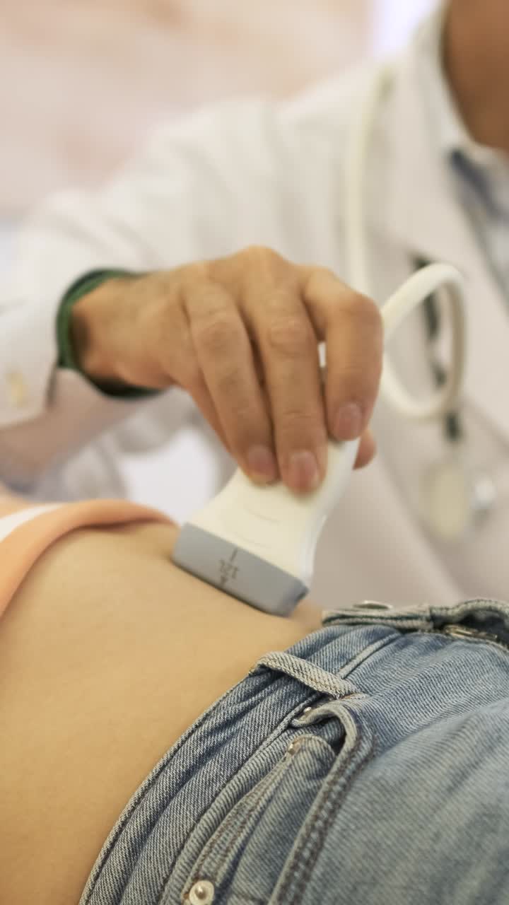 Doctor pouring gel on stomach then doing ultrasound