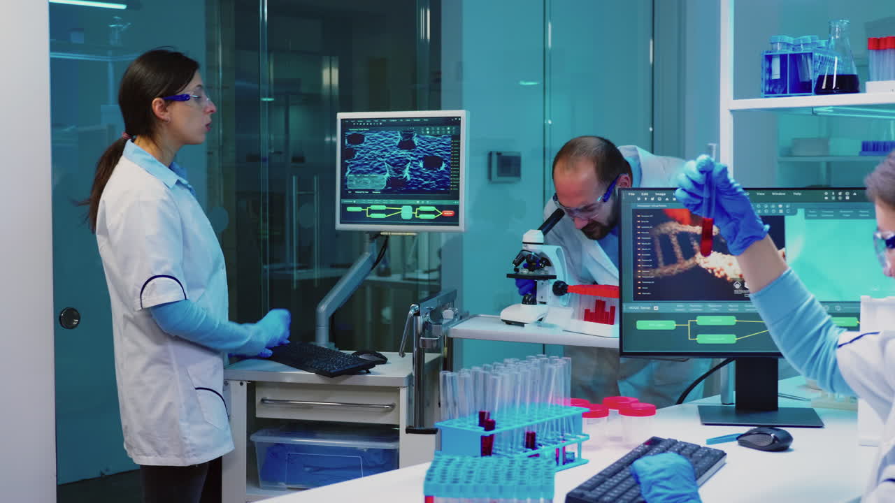 Researcher using microscope in laboratory while nurse taking notes