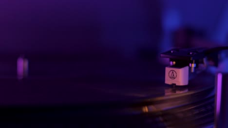 close up of a vinyl record player spinning with cinematic purple and blue lighting