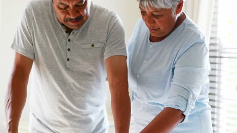 Senior-woman-helping-man-to-walk-with-a-walker-4k