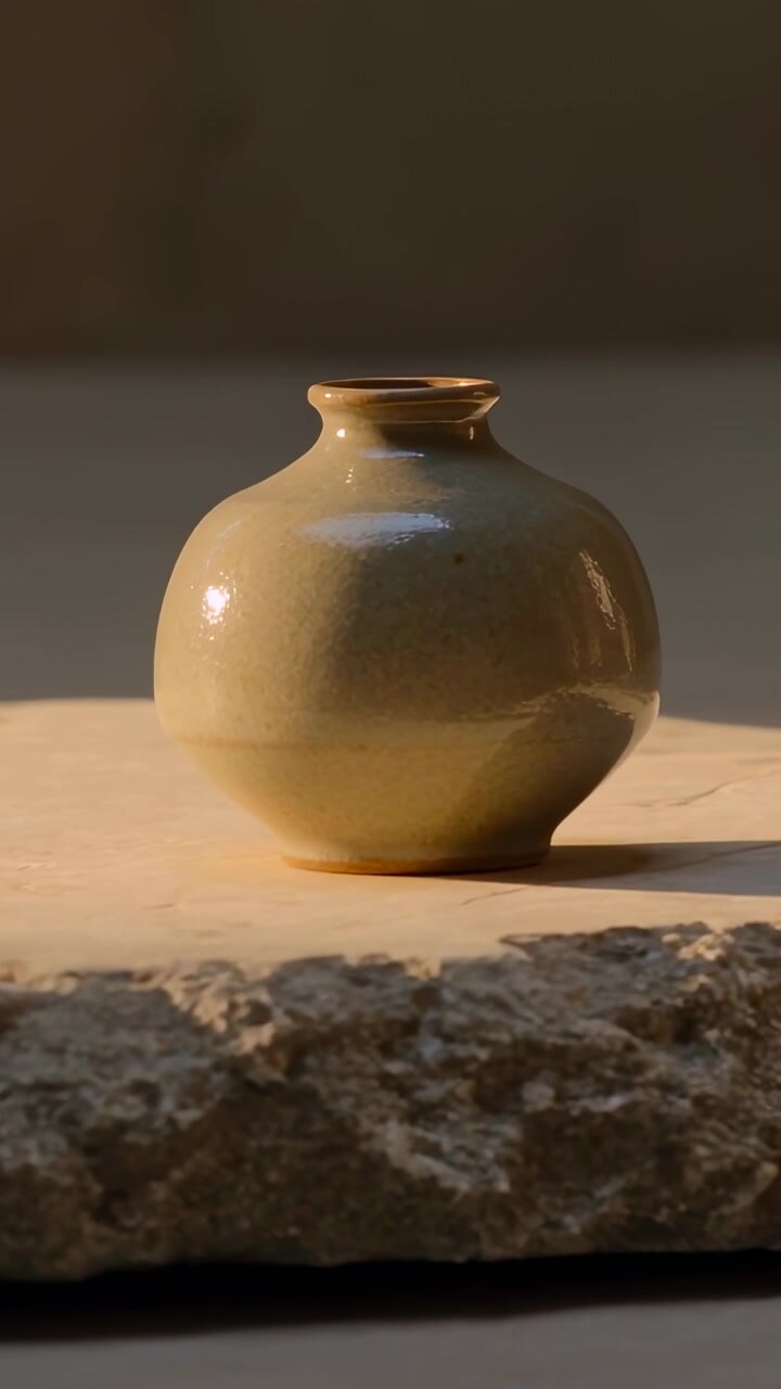 Vertical video: Tightening camera bringing glazed vase closer on tabletop to reveal stone texture