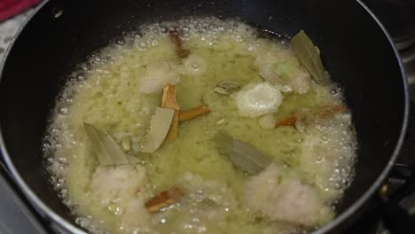 cebollas fritas con canela y hojas de laurel en una sartén, de cerca