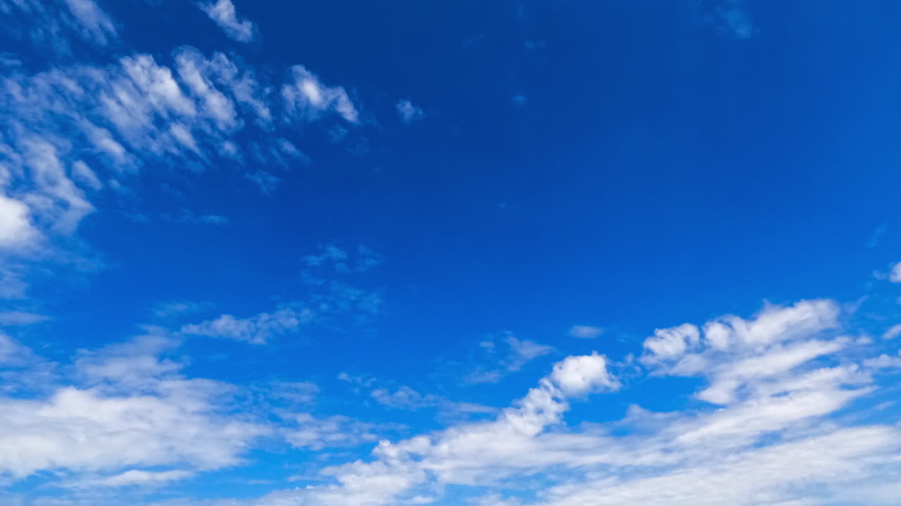 Altocumulus and stratocumulus clouds in the azure sky. Low angle view on the white clouds moving in the wind. Timelapse.