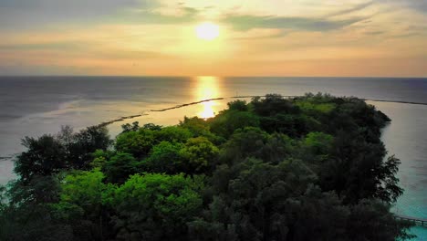 Tropical-island-on-a-turquoise-ocean-waters-aerial-view-during-sunset-on-the-horizon