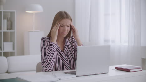 mujer está hablando en línea por chat de video y sintiendo dolor de cabeza tocando las sienes y haciendo caras migraña en el tiempo de trabajo