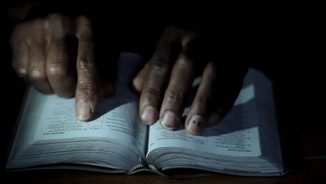 praying-to-God-with-hand-on-bible-black-background-with-people-stock-footage