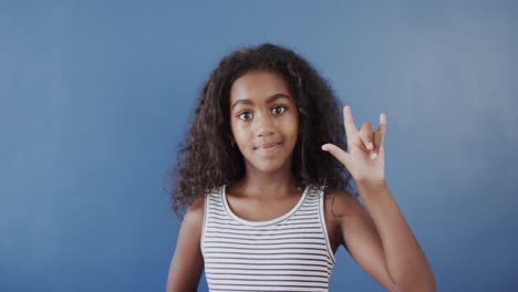 Happy-african-american-girl-using-sign-language-on-blue-background,-slow-motion