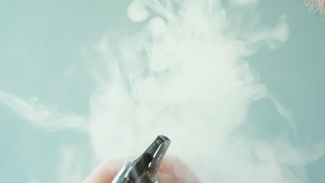 Close-up of a man exhaling vapor while using an electronic cigarette. Concept of vaping, nicotine alternatives, modern smoking habits, and e-cigarette lifestyle