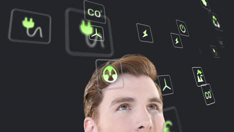 animación de múltiples iconos digitales sobre un hombre caucásico mirando hacia arriba contra un fondo gris