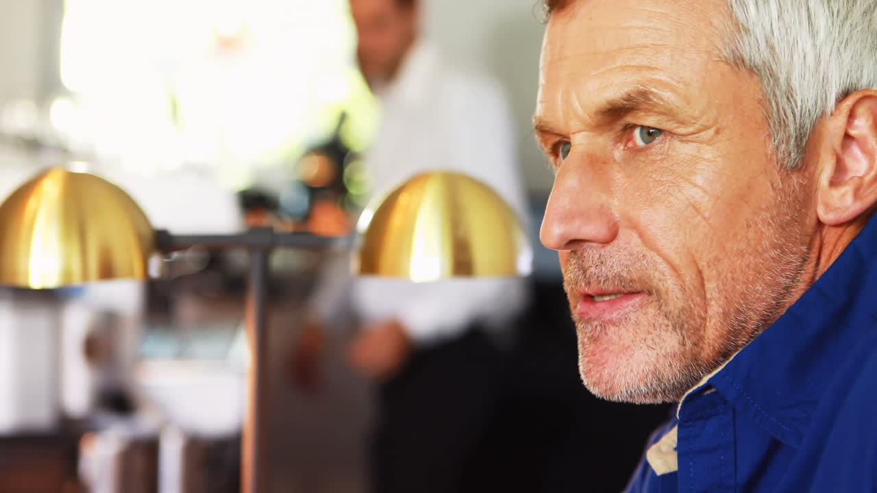 미소 짓는 성숙한 남자가 카운터에서 맥주를 마시고 있습니다.