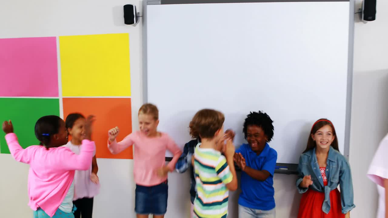 Schoolteacher and kids giving high five in classroom
