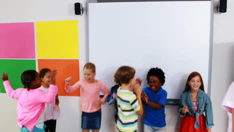 schoolteacher and kids giving high five in classroom