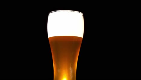 fresh bubbly beer with foam in a pilsner glass isolated in black background with smoke - studio shot