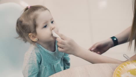 young beautiful mother with her little daughter sitting in a cafe mom wipes her mouth with a napkin