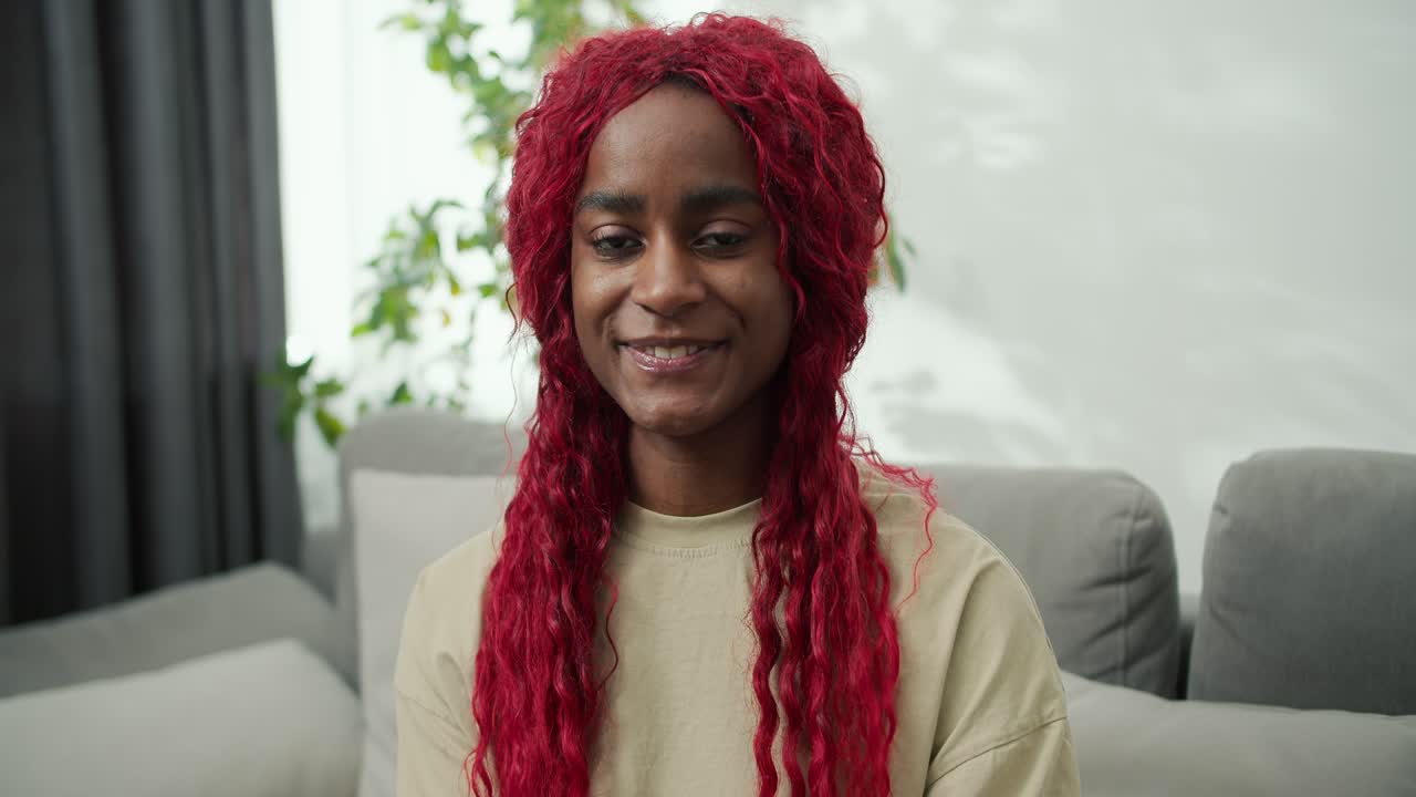retrato de una mujer afroamericana sonriente con el cabello rojo elegante en casa