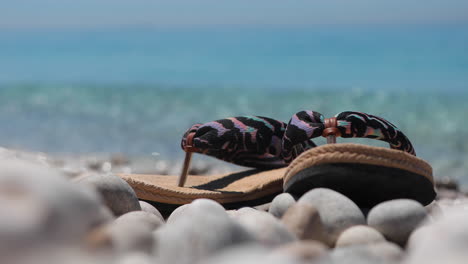 foto de concepto de vacaciones, chanclas en una tranquila playa de guijarros con fondo de mar esmeralda