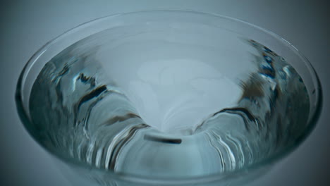 closeup ice aqua making funnel inside glassware. container with rotating liquid