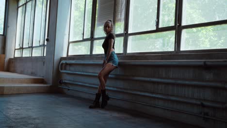 Thoughtful tattooed woman looking into the camera and posing in natural light, wearing hot pants