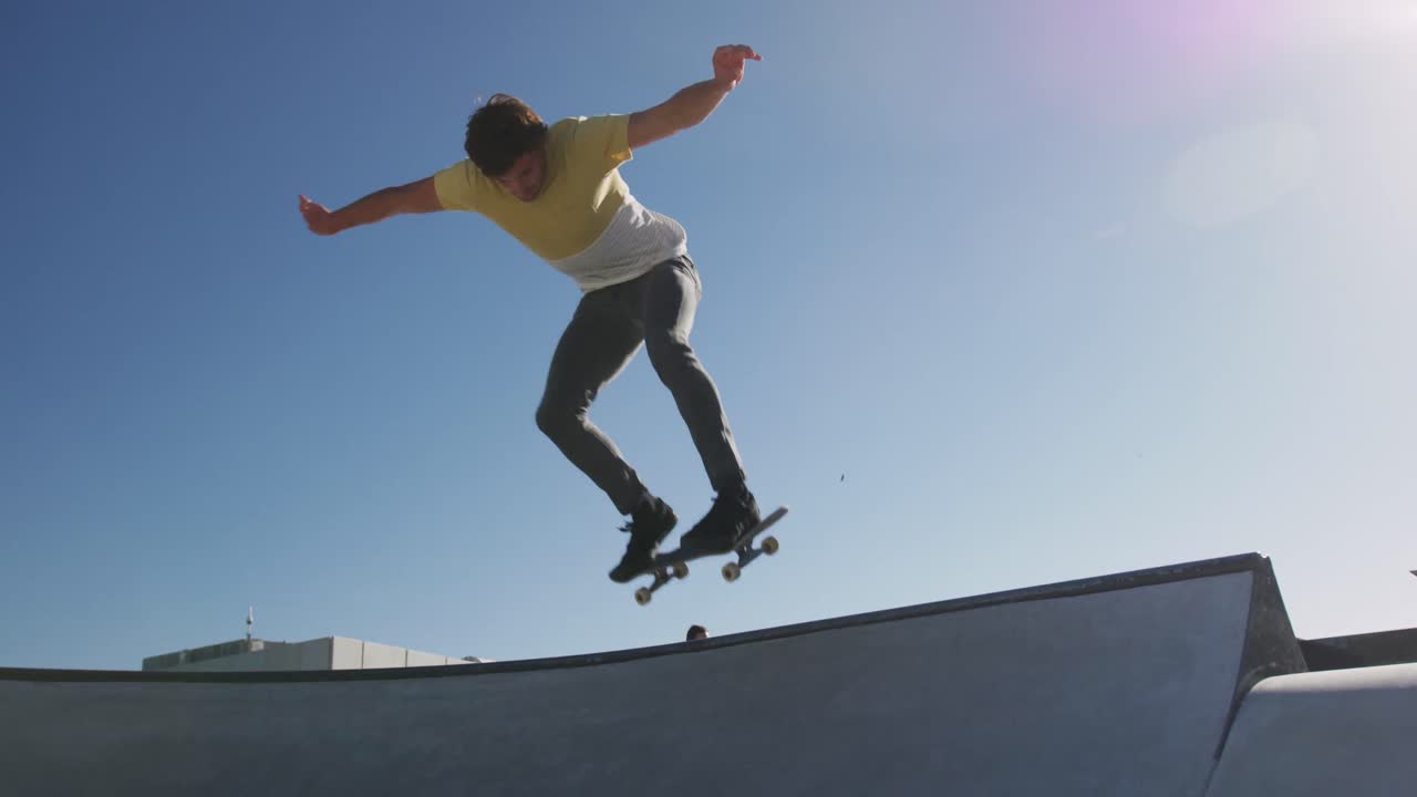Uomo caucasico che va e salta sullo skateboard in una giornata di sole
