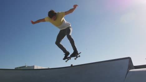 caucasian man riding and jumping on skateboard on sunny day