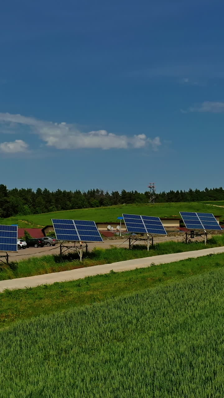 Photovoltaic solar panels on nature background. Blue sunny batteries along the road on green field. Sustainable source of clean energy. Vertical video