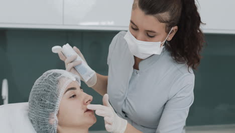 beautician applying a cosmetic treatment to a woman's lips