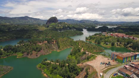 drone flying towards famous rock of guatape landmark and it's lake surroundings