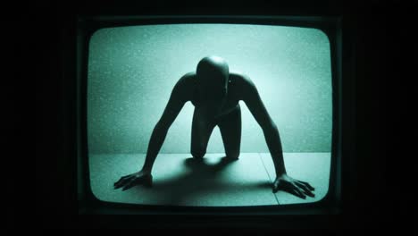 a mysterious figure is seen crawling on a floor, illuminated by a green glow from an old tv screen, creating an unsettling and eerie atmosphere in the darkened room