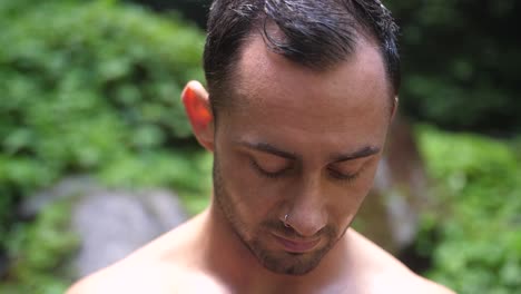 Un-Hombre-Joven-Y-Atractivo-Con-Una-Expresión-Facial-Seria,-Mirando-A-La-Cámara-Y-A-Su-Alrededor-En-La-Exuberante-Y-Verde-Jungla-De-Bali