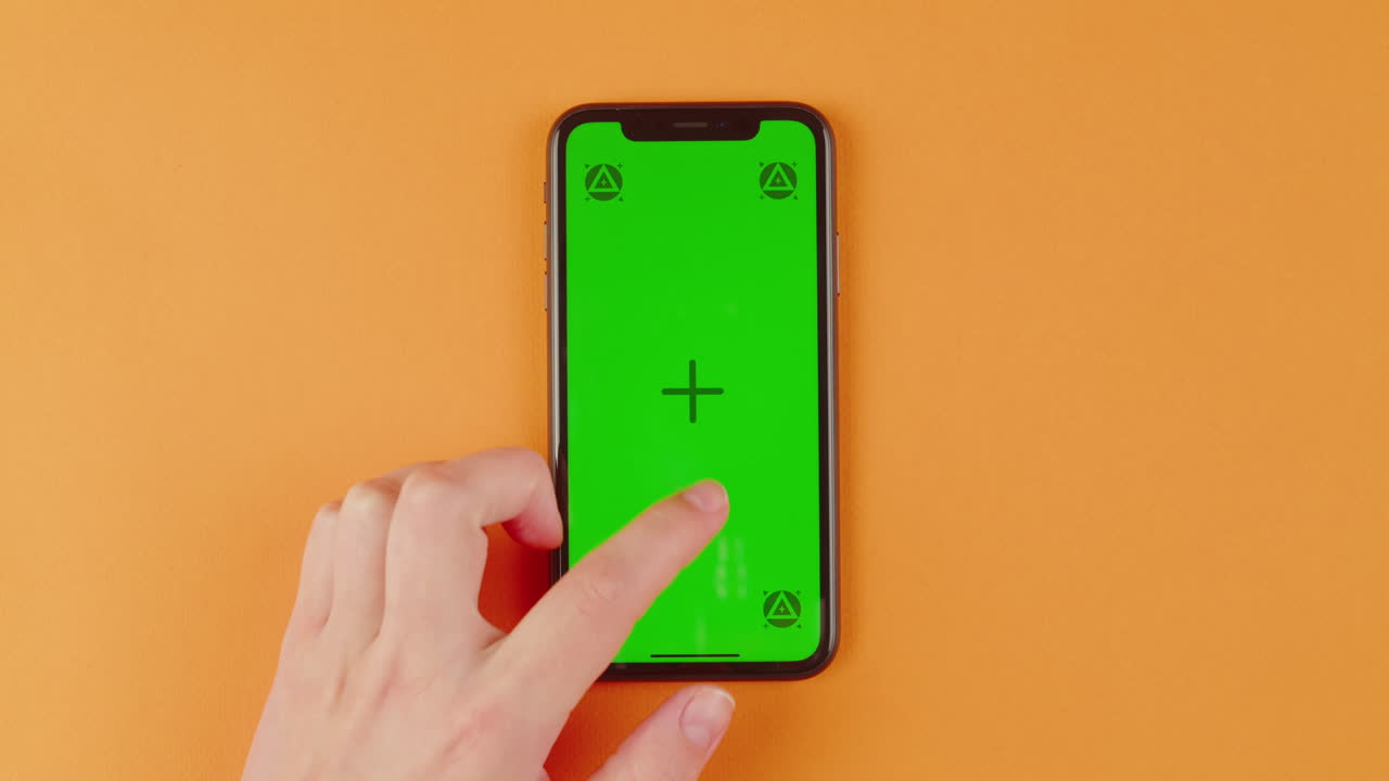Hand touching a smartphone with a green screen display
