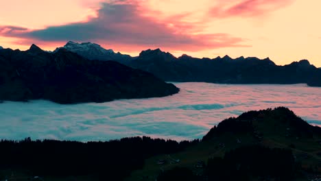 slow dolly timelapse of the vibrant sunset shining over the fog-covered mountain range in the swiss alps