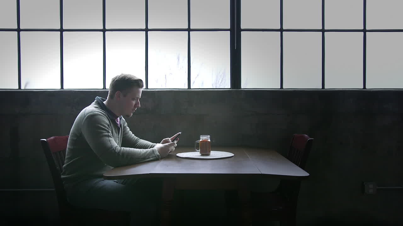 Man Sitting at a Table Using a Cell Phone