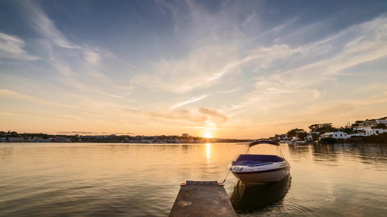 Singola barca ancorata nel porto di Mahon durante il tramonto a Minorca, Spagna. Timelapse