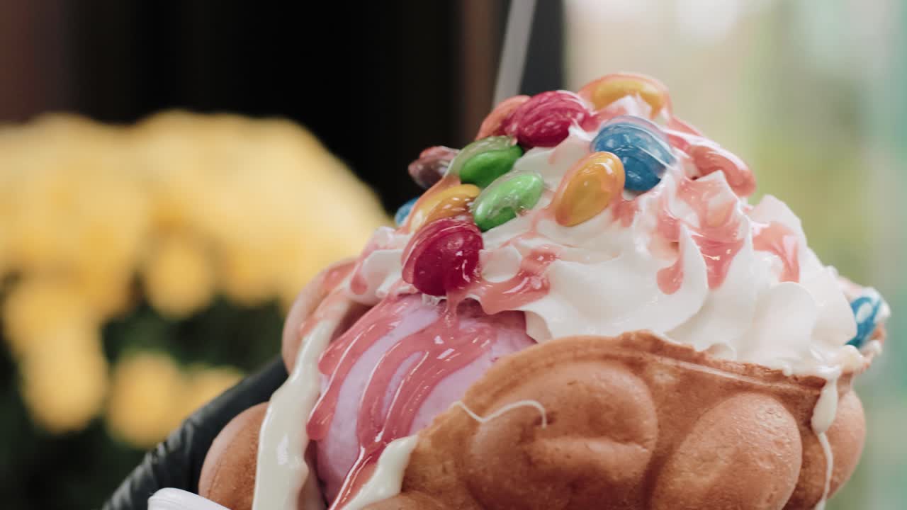 Versare crema alla frutta su un bubble waffle con caramelle