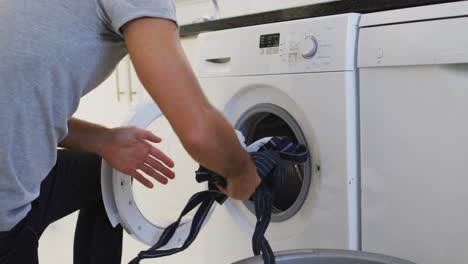 caucasian man putting apron in the washing machine at home